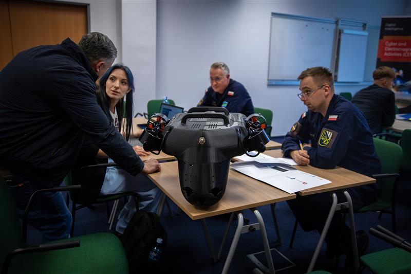 Uczestnicy i uczestniczki IDA Bootcamp rozmawiający przy stoliku.